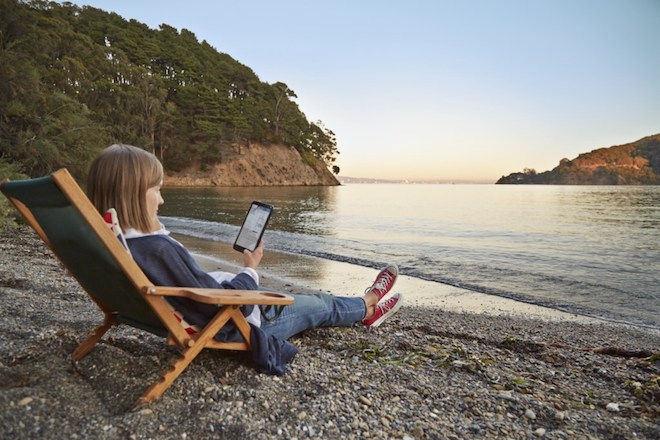 Woman works on HP Stream 8 tablet while sitting on the beach.